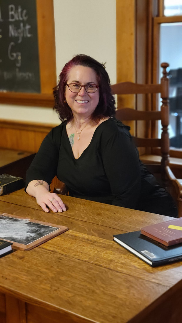 Susan McCarthy, professional organizer and founder of A Less Cluttered Life sitting at an old fashioned desk, representing her former career as a teacher.