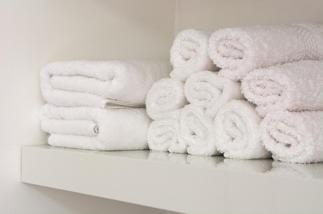 A shelf of neatly stacked towels shows one of the purposes of decluttering.
